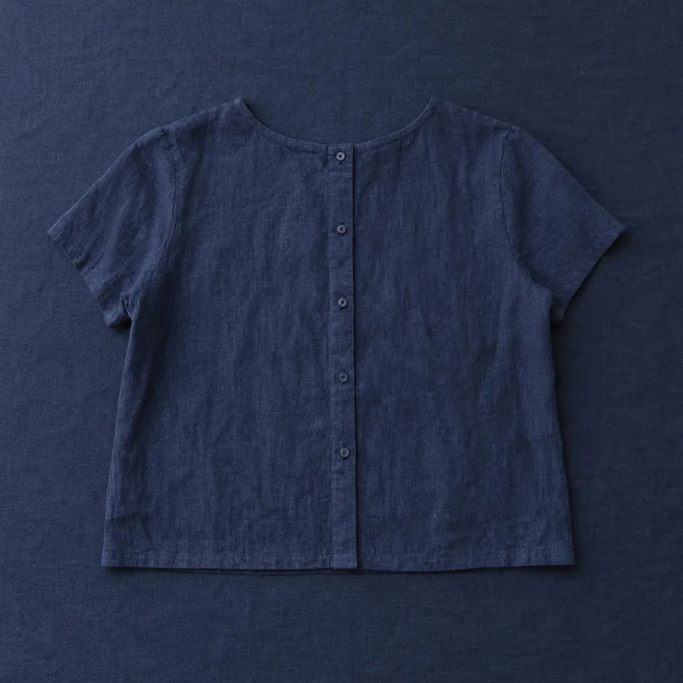 Blusa de ramio Santo Domingo, azul marino, extendida sobre un mantel azul oscuro