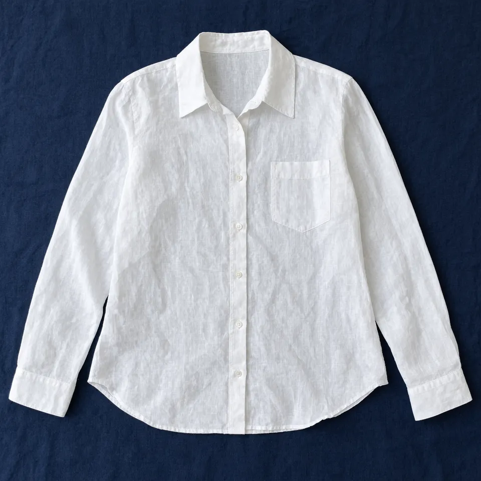 Camisa de lino San Andrés, blanco óptico, extendida sobre un mantel azul oscuro