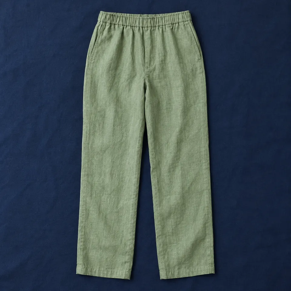 Pantalón de lino El Carmen, verde salvia, extendida sobre un mantel azul oscuro