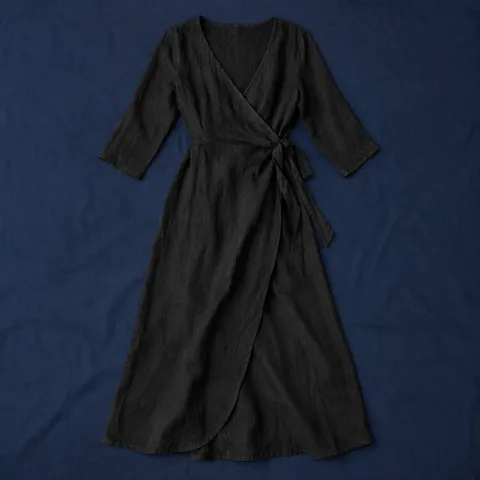 Vestido cruzado Monteagudo en negro, prenda extendida sobre mantel azul